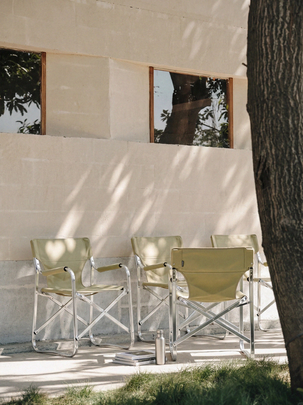 Sage-green Onway Sports director chairs in a sunlit courtyard