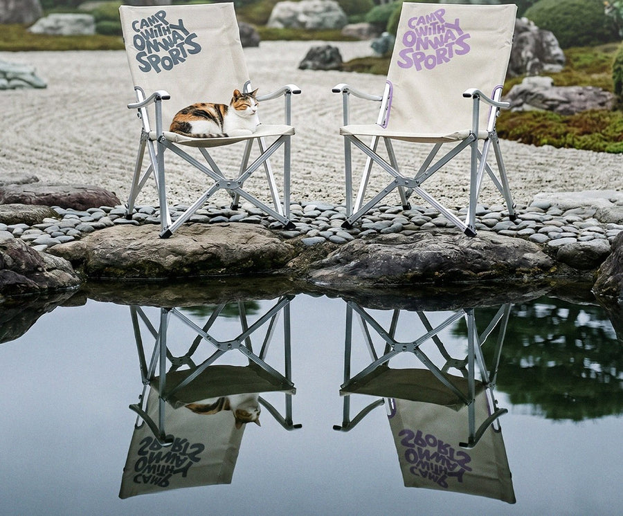 Two Onway Sports folding chairs beside a zen garden pond, a cat asleep on one seat